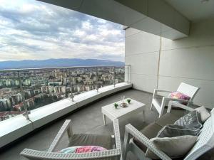 uma varanda com cadeiras, uma mesa e uma vista em Skopje Sky Apartment 32nd floor em Skopje