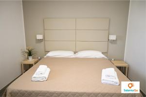 una camera da letto con un grande letto con due asciugamani di Stanze VILLA DEL CONTE a Punta Prosciutto by SalentoGo a Punta Prosciutto