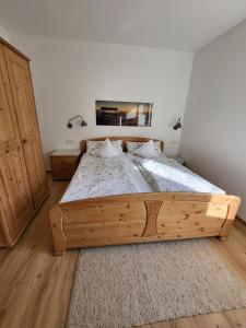 a large wooden bed in a bedroom with two lamps at Ferienwohnungen Rodler in Bergen
