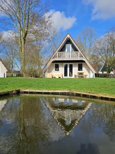 a house with a pond in front of it at 6 pers. vakantiehuis aan visvijver op vakantiepark, Time4vacay in Gramsbergen