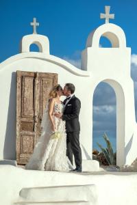 a bride and groom kissing in front of a church at Axiotheaton Villas in Pefki Rhodes