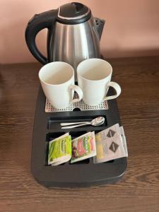 a coffee maker with two cups and tea packets at Boutique Hotel Sopianae in Pécs
