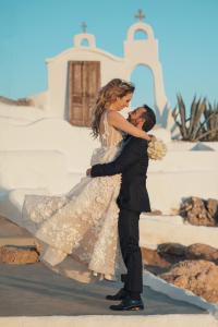 una novia y un novio bailando frente a una iglesia en Axiotheaton Villas, en Pefki