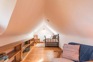 a attic room with a couch and a crib at Little Ripple Cottage by Bloom Stays in Canterbury