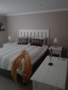Un dormitorio con una gran cama blanca y una mesa en K Partners' Boutique Hotel & Spa, en Langebaan