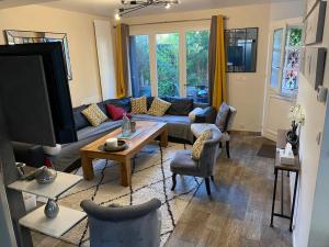 uma sala de estar com um sofá e uma mesa em Superbe Maison avec Terrasse près de PARIS (RER A) em Carrières-sur-Seine