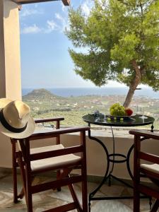 una mesa con sombrero y sillas en el balcón con vistas en Homey Stoupa, Mani, en Stoupa