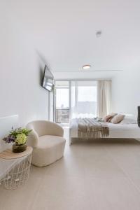1 dormitorio blanco con 1 cama y 1 silla en Modern studio near the beach, en Ostende