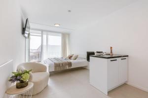 Habitación blanca con cama y silla en Modern studio near the beach, en Ostende