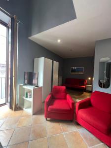 ein Wohnzimmer mit 2 roten Stühlen und einem TV in der Unterkunft Naples Luxury Suites B&B in Neapel