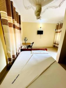 a bedroom with a large bed with a ceiling at Agabet Hotel - Mbale in Mbale