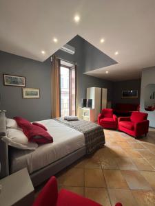 um quarto com uma cama grande e 2 cadeiras vermelhas em Naples Luxury Suites B&B em Nápoles