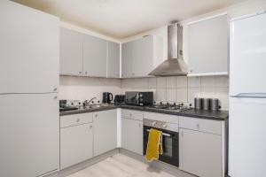 Biała kuchnia z białymi szafkami i urządzeniami w obiekcie Heads-On-Beds Rainham Essex - 4Bedrooms with Garden w mieście Rainham