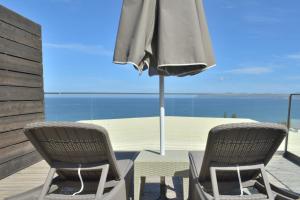 two chairs and an umbrella on a deck with the ocean at Galini Sea View Hotel in Agia Marina Nea Kydonias