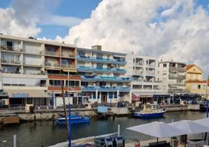 a large apartment building next to a marina with boats at Magnifique logement d'architecte 3* sur Palavas in Palavas-les-Flots