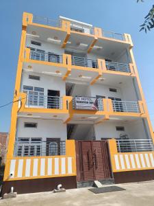 un grand bâtiment avec des balcons orange et blanc dans l'établissement Hotel Ramayan Inn Free Pickup From Ayodhya Dham Junction, à Ayodhya