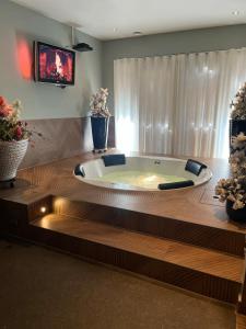a large bath tub in a room with a tv at Priscilla’s bed&wellness in Eindhoven