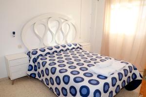 a bedroom with a bed with a blue and white comforter at Apartamento Luna Llena Golf de San Juan de los Terreros in San Juan de los Terreros +34 photos