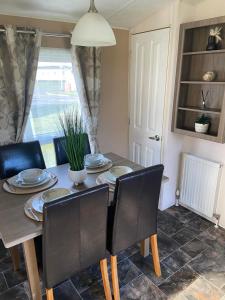 une table à manger avec des chaises noires et une table dans l'établissement Impeccable 2-Bed Lodge in Ashington, à Ashington