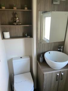 La salle de bains est pourvue d'un lavabo blanc et de toilettes. dans l'établissement Impeccable 2-Bed Lodge in Ashington, à Ashington