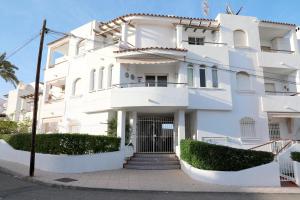 um edifício branco com um portão em frente em Apartamento Luna Llena Golf de San Juan de los Terreros em San Juan de los Terreros