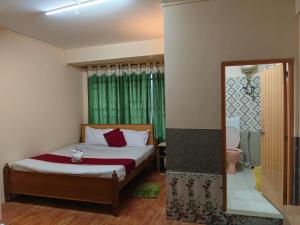 Schlafzimmer mit einem Bett, einem WC und einem Spiegel in der Unterkunft Balaji Continental in Shillong