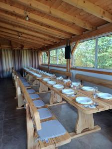 uma longa mesa de madeira com pratos brancos e copos de vinho em Medeni raj em Mače