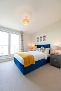 um quarto com uma cama azul e 2 janelas em Modern 2 Bed Apartment in Crawley - Sleeps 5 em Crawley