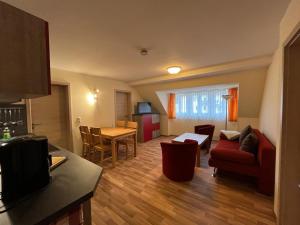 a living room with a red couch and a table at Pension Am Finkenberg in Sebnitz