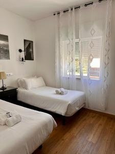 2 camas en una habitación con cortinas blancas y ventana en Castelo da Esperança na Vila Sra da Rocha en Porches