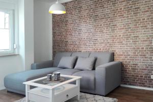 a living room with a couch and a brick wall at Fewo Dobra in Lübbenau