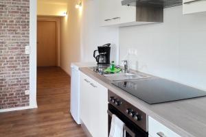 a white kitchen with a sink and a brick wall at Fewo Dobra in Lübbenau