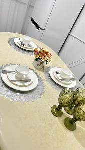stół z talerzami, kubkami i kwiatami w obiekcie Апартаменты посуточно w mieście Atyrau