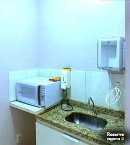 a kitchen counter with a microwave and a sink at FLAT Golden Dolphin Express in Caldas Novas