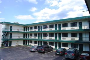 um grande edifício branco com carros estacionados num parque de estacionamento em Travelodge by Wyndham Chambersburg em Chambersburg