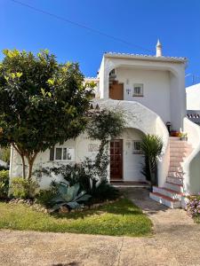 une maison blanche avec une porte rouge et un arbre dans l'établissement Castelo da Esperança na Vila Sra da Rocha, à Porches