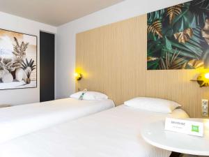 Zimmer mit 2 Betten, einem Tisch und einem Gemälde in der Unterkunft ibis Styles Troyes Centre in Troyes