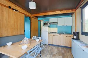 uma cozinha com uma mesa de madeira e um frigorífico em Camping La Pinède em Excénevex