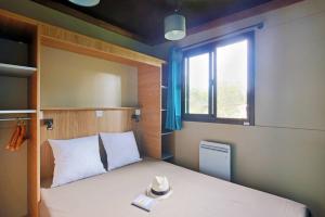 a bedroom with a bed with a window and a hat at Camping La Pinède in Excénevex