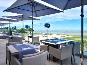 a restaurant with tables and chairs with a view of the beach at La Grande Terrasse Hotel&Spa La Rochelle MGallery Hotel Collection in Châtelaillon-Plage