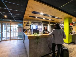 Una mujer parada en una barra de un restaurante en ibis budget Paris Clichy Mairie, en Clichy