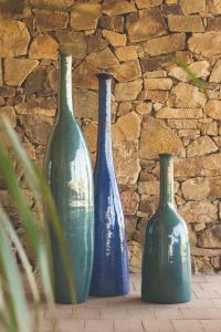 three blue vases sitting in front of a stone wall at Hotel Aquadulci in Chia