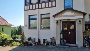 una casa blanca con una puerta marrón y algunas plantas en Haus Sonneck, en Bad Sachsa