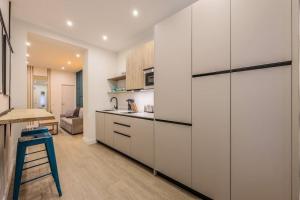une cuisine avec des placards blancs et un tabouret bleu dans l'établissement Luxe Apartment in Malasaña Hub, à Madrid