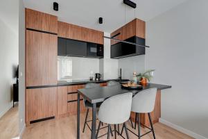 uma cozinha com uma mesa preta e cadeiras brancas em Lion Apartments - Młoda Polska Nowy Apartament z parkingiem em Sopot