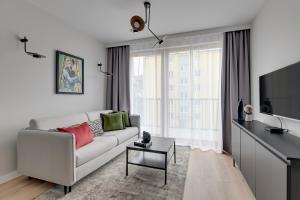 uma sala de estar com um sofá e uma televisão em Lion Apartments - Młoda Polska Nowy Apartament z parkingiem em Sopot