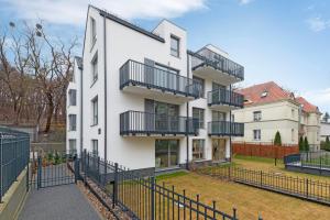 um edifício de apartamentos com varandas e uma cerca em Lion Apartments - Młoda Polska Nowy Apartament z parkingiem em Sopot