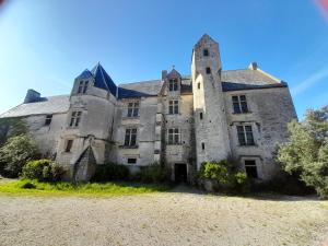 um velho castelo com uma torre num campo em 6, route de Maisons Manoir d'Argouges em Vaux-sur-Aure