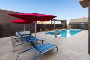 a group of chairs and umbrellas next to a pool at Hawthorn Extended Stay by Wyndham Kingwood Houston in Kingwood