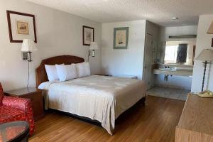a hotel room with a bed and a red chair at Howard Johnson by Wyndham Azusa in Azusa